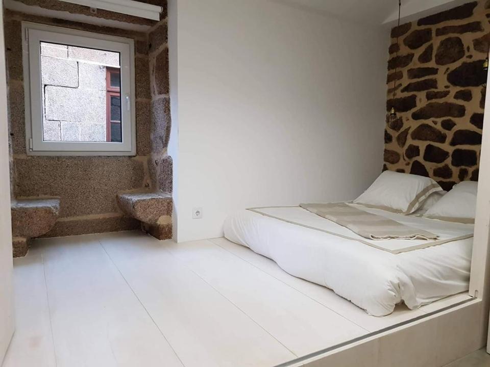 Cama en habitación blanca con ventana en Casa do Doutor Palheiro, en Travassos