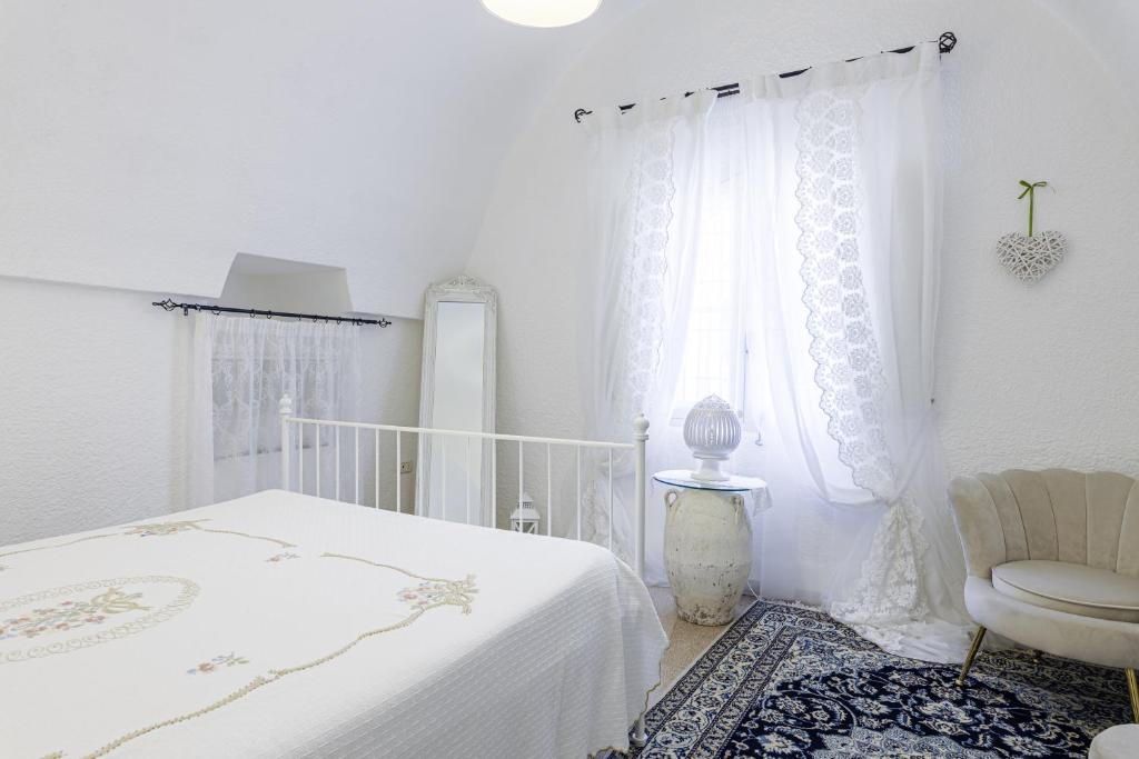 ein weißes Schlafzimmer mit einem Bett und einem Stuhl in der Unterkunft Andrew'S home - Luisanna in Torre Pali 