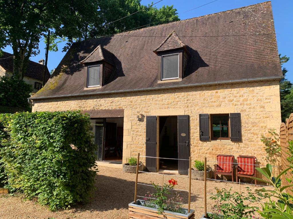 una casa con dos sillas rojas delante en Gîte - Le Petit Noyer, en Le Bugue