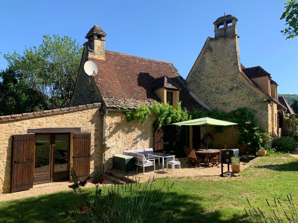 een huis met een tafel en een paraplu in de tuin bij Gîte - Le Reclaud du Noyer in Le Bugue