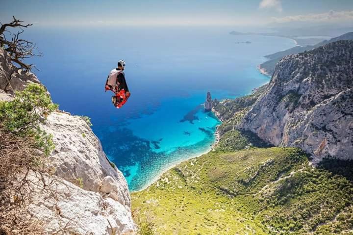 a person jumping off of a cliff overlooking the ocean at Casa Cala Luna in Santa Maria Navarrese