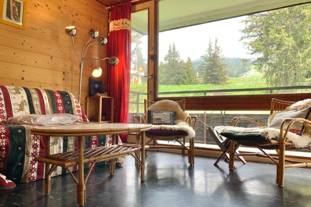 a living room with a table and chairs and a large window at The Chamroussian #BU in Chamrousse