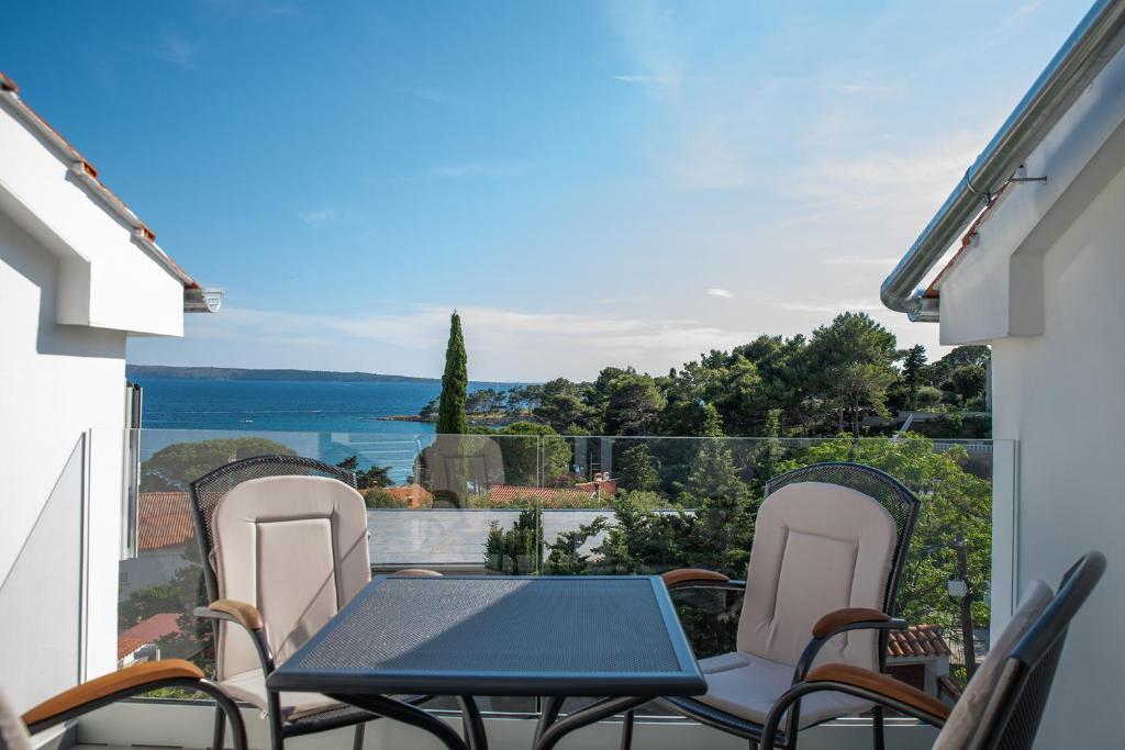 una mesa y sillas en un balcón con vistas al océano en Apartmani Vrtodusic, en Rab