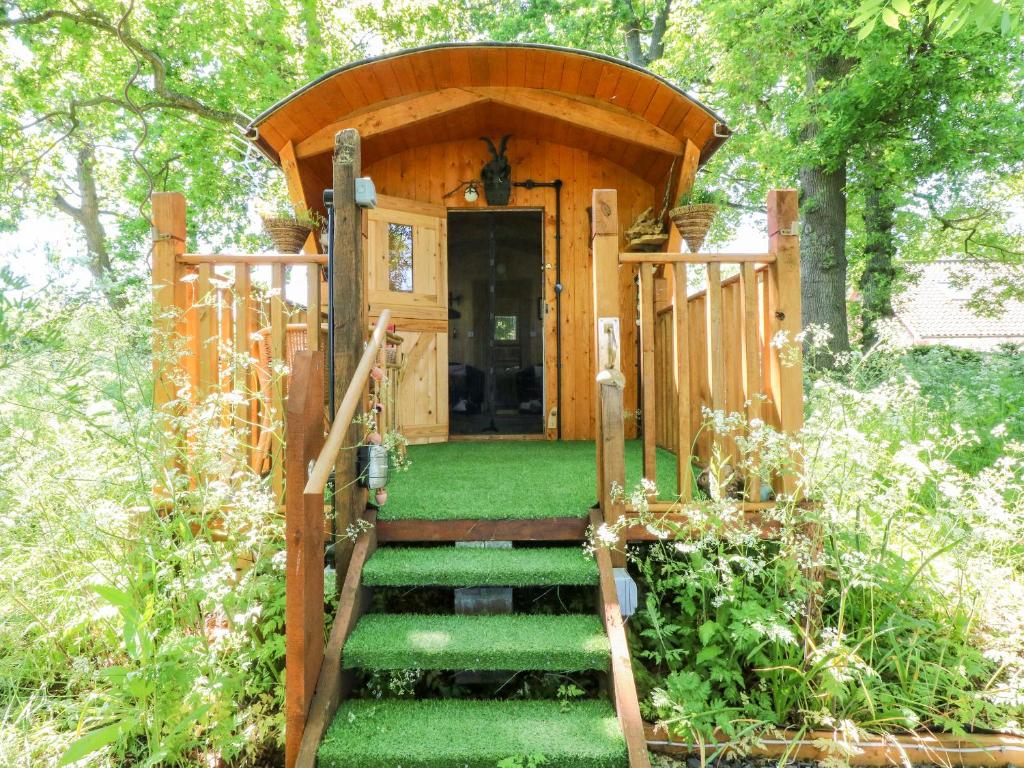 eine Holzhütte mit einer Treppe, die zu einer Tür führt in der Unterkunft Hugatree in Little Dunham