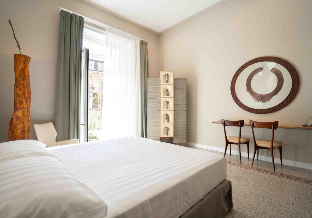 ナポリにあるAtelier Inès Arts & Suitesのベッドルーム1室(ベッド1台、テーブル、椅子付)