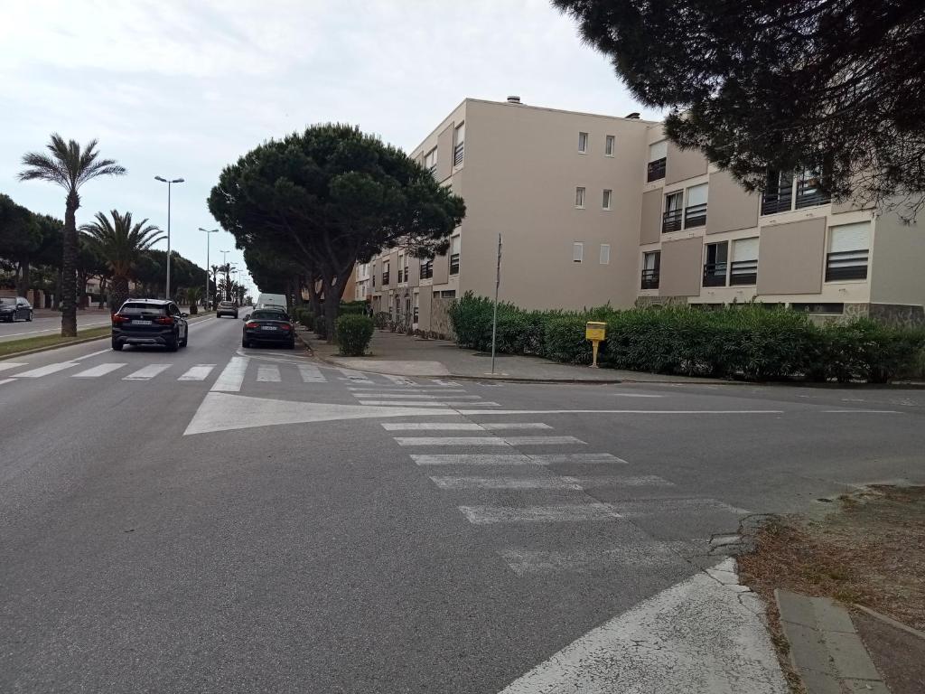 Une rue vide avec un bâtiment et des voitures sur la route dans l'établissement Le liberté plage et port, à Saint-Cyprien