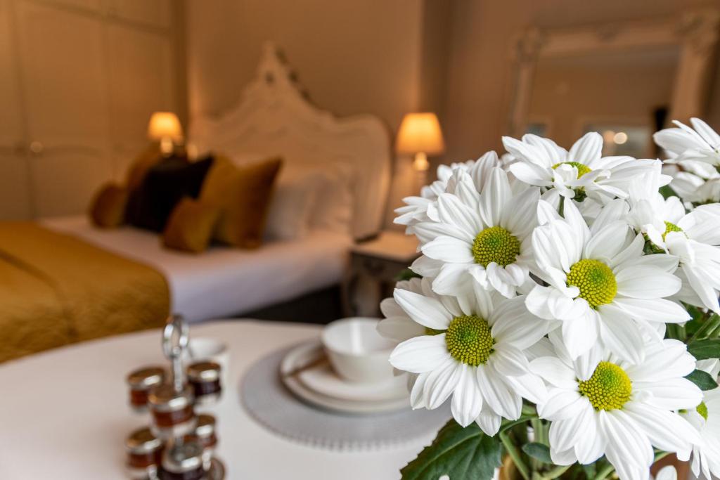 eine Vase mit weißen Blumen auf einem Tisch im Schlafzimmer in der Unterkunft Apple Tree Bed and Breakfast in Tavistock