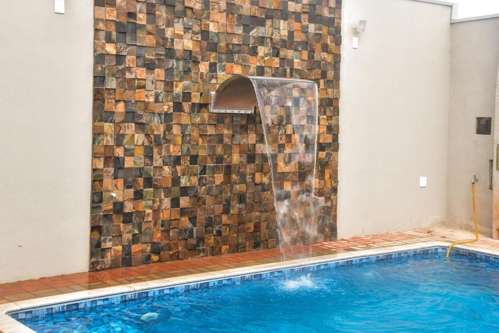a swimming pool with a brick wall next to a swimming pool at Casa com piscina e Wi-Fi em Itapetininga in Itapetininga