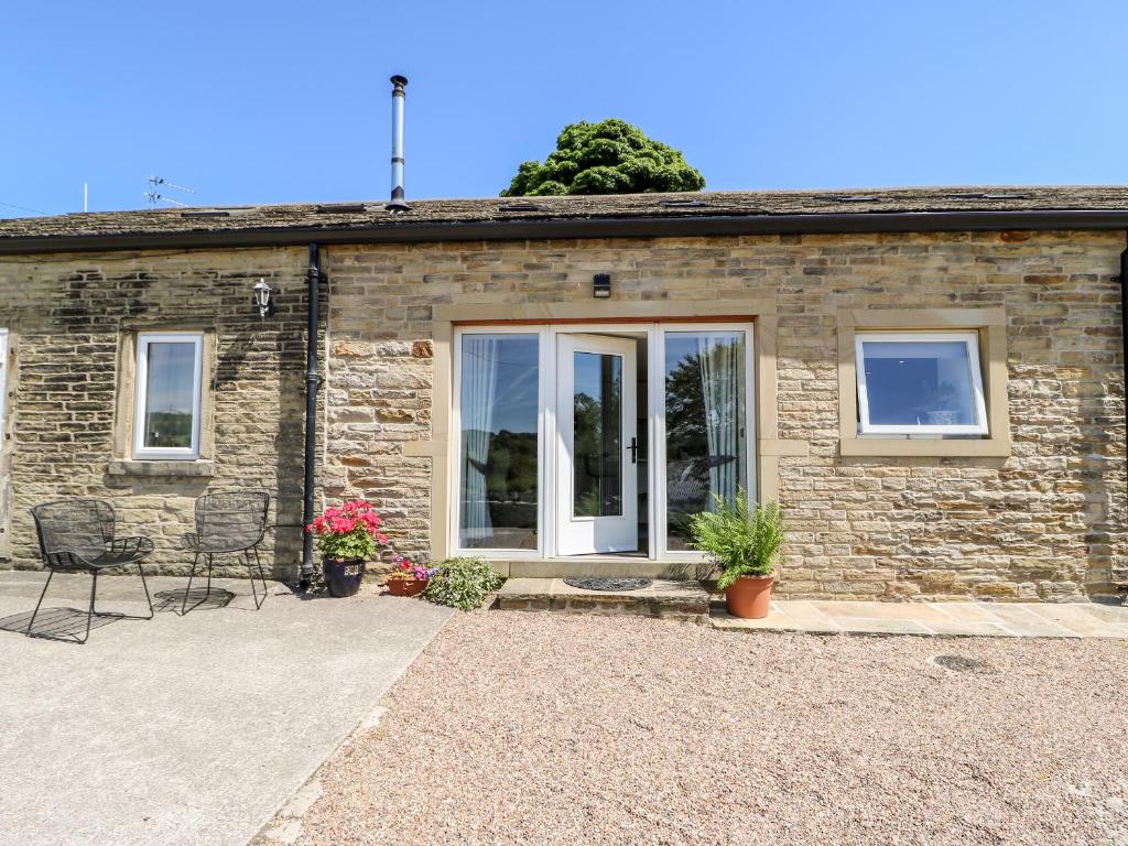 a stone house with windows and chairs in front of it at 1 Barn Cottages in Halifax