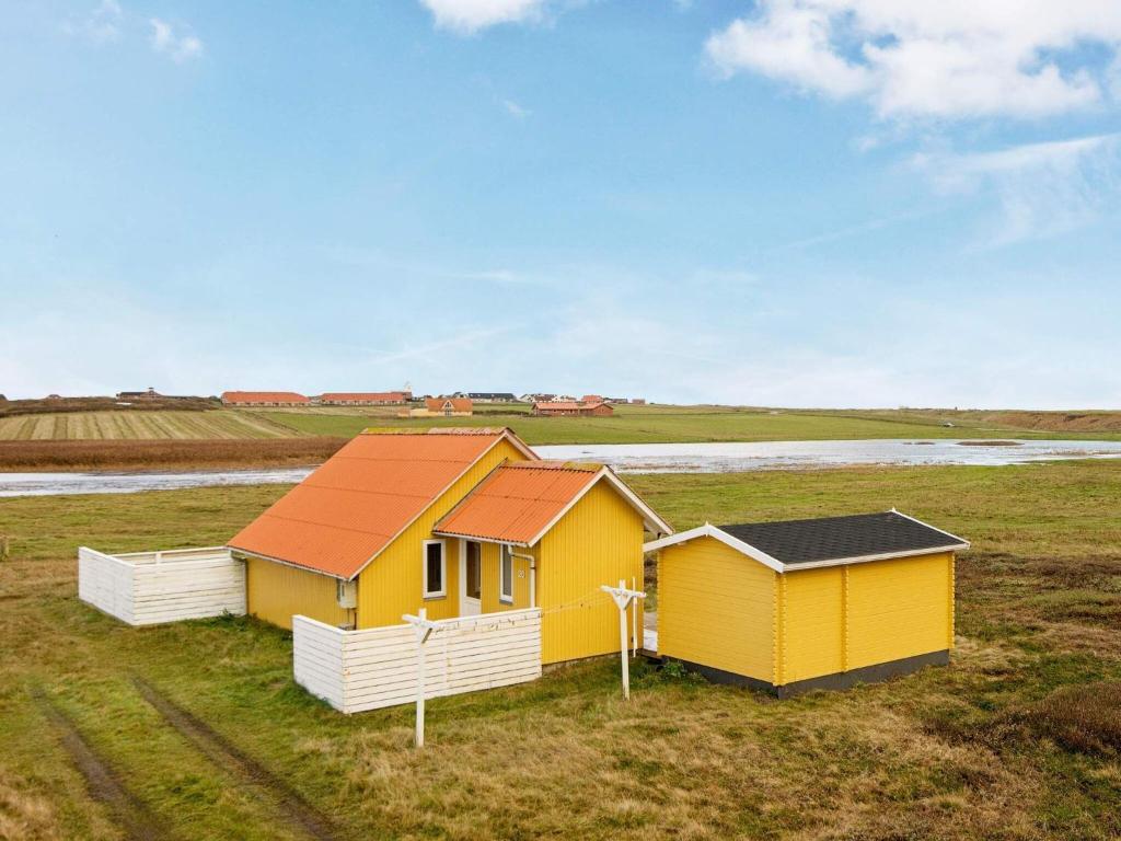 a yellow house with a red roof in a field at 5 person holiday home in Lemvig in Lemvig