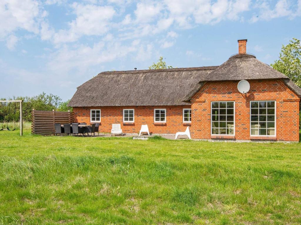 a red brick building with a grass field in front of it at Four-Bedroom Holiday home in Ulfborg 9 in Øby