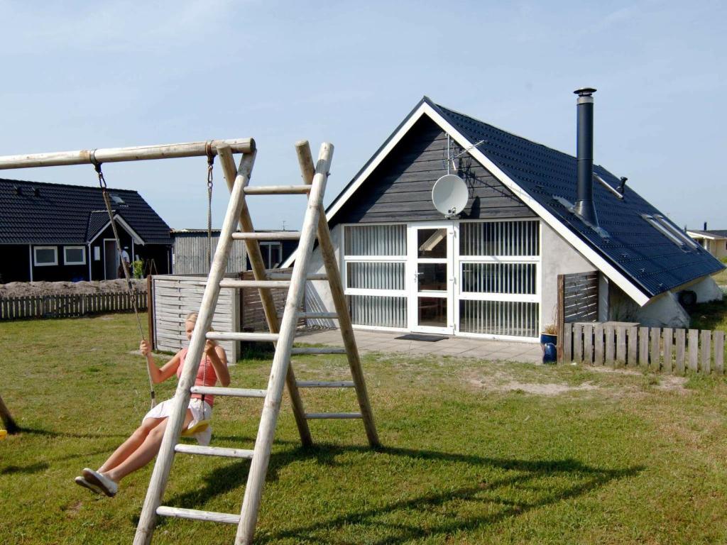 a woman sitting on a swing in front of a house at 6 person holiday home in Harbo re in Harboør