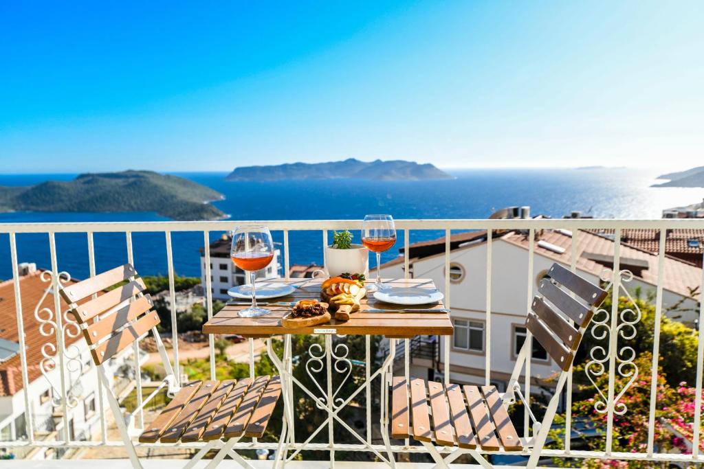 a table with wine glasses on a balcony overlooking the ocean at Kybele Suites in Kaş