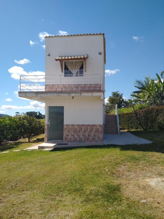 a white house with a balcony on top of a yard at Recanto das Videiras in Maria da Fé