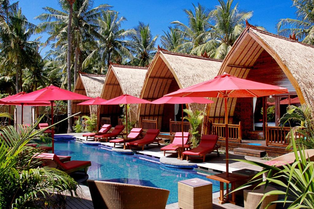 ein Resortpool mit Stühlen und Sonnenschirmen in der Unterkunft D'Wahana Resort in Gili Trawangan
