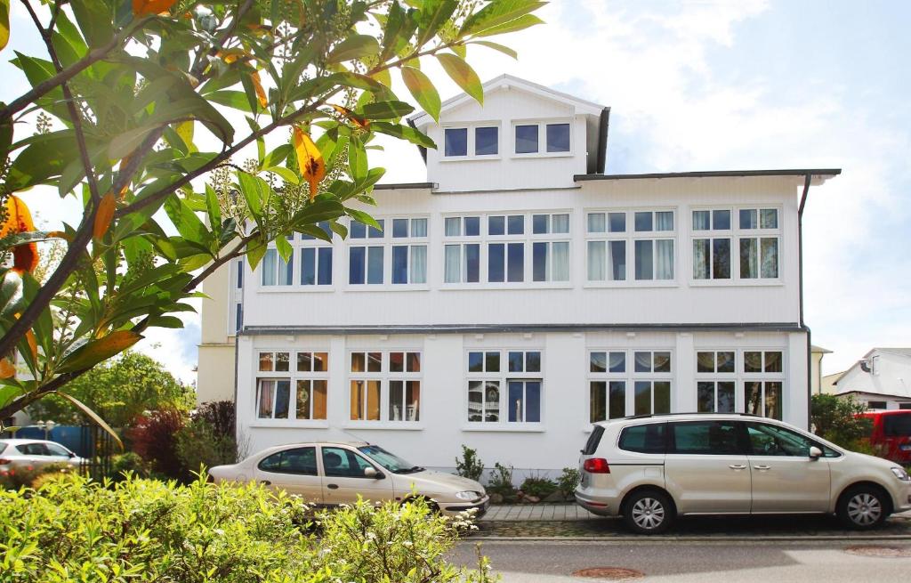 a white house with two cars parked in front of it at F-1093 Villa Elise Ferienwohnung Nr 01 in Göhren