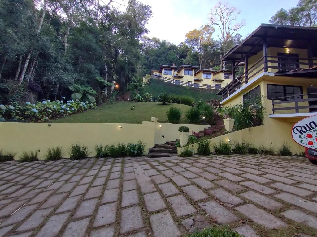 un patio trasero de una casa con una entrada de ladrillo en Villa de charme suítes en Monte Verde