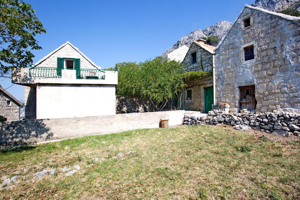 ein altes Steinhaus mit einer Steinmauer in der Unterkunft House Tina in Omiš