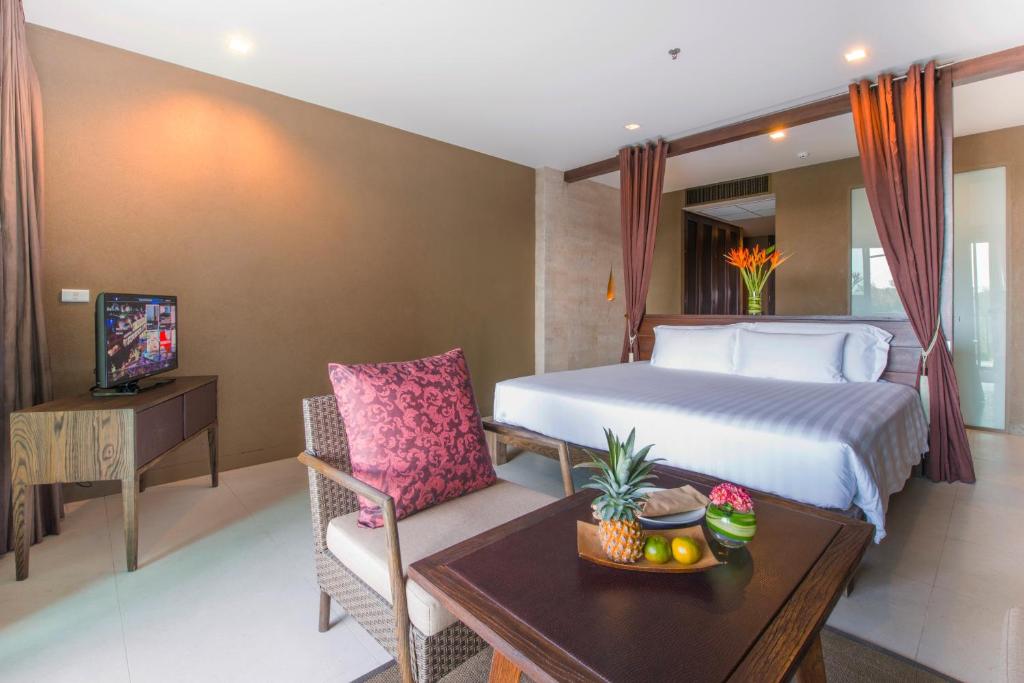 a hotel room with a bed and a table with a table at Sunsuri Phuket - SHA Plus in Nai Harn Beach