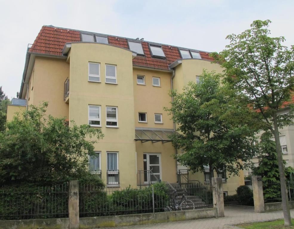 een geel gebouw met een rood dak bij Apartment am Großen Garten Dresden in Dresden