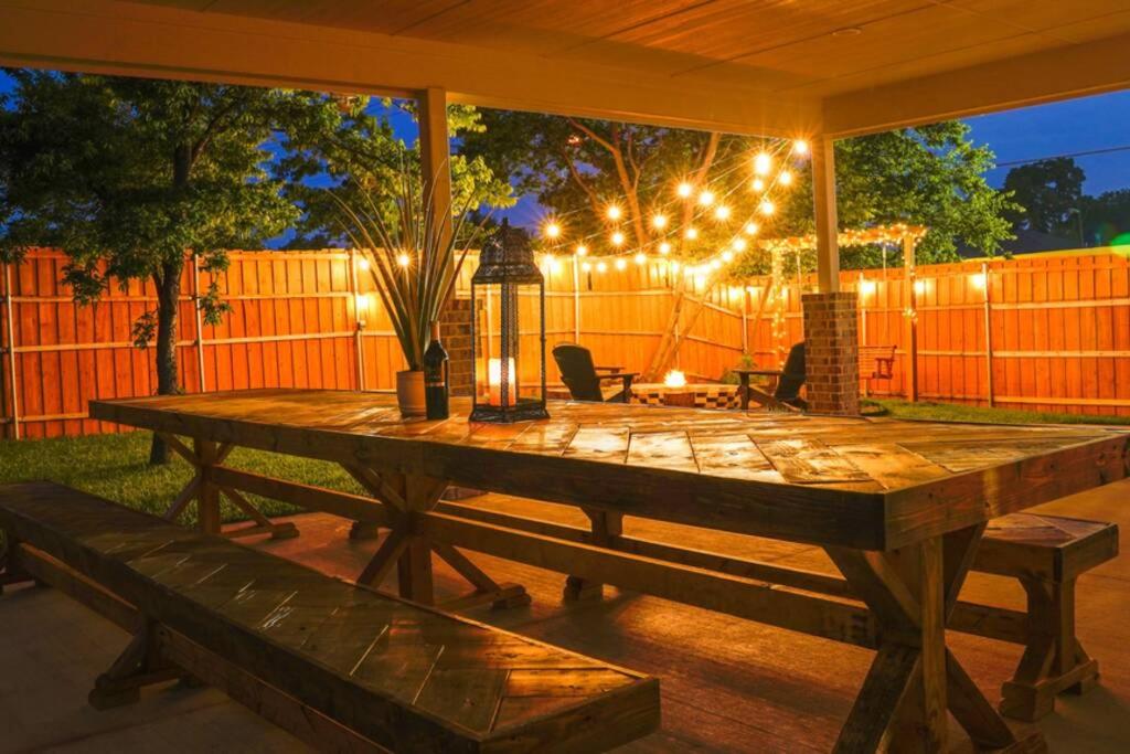 a wooden table in a backyard with lights on it at Dallas 4BR Large yard w HOT TUB , Fire pit and basketball Hoop in Dallas
