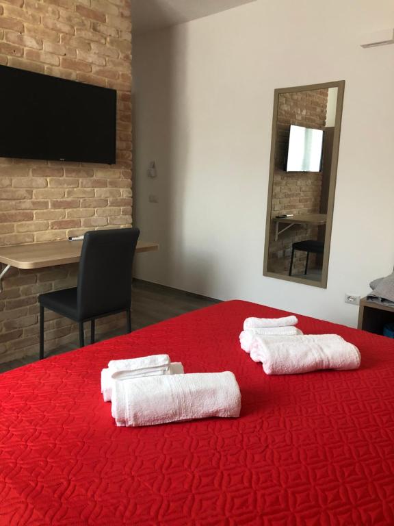 Habitación con cama roja y toallas. en Affittacamere Su Caboni en Tortolì