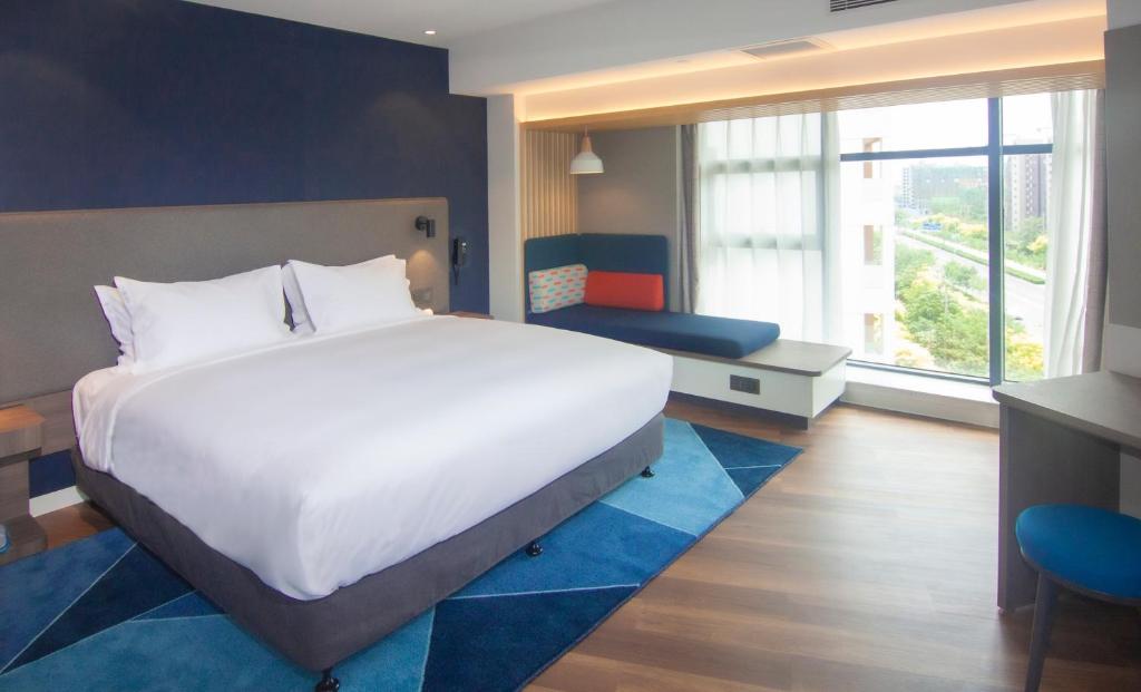 a bedroom with a large white bed and a window at Holiday Inn Express Tianjin Airport East, an IHG Hotel in Tianjin