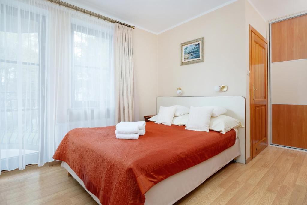 a white bedroom with a bed with red blanket and white pillows at Willa u Wójta in Pobierowo