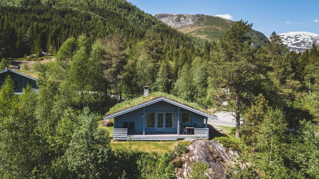 a blue house in the middle of a mountain at Jølsterlia Hyttetun in Årdal