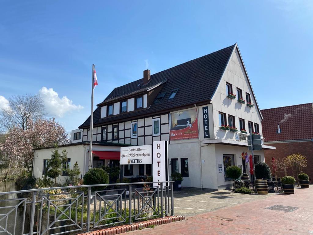 un grand bâtiment blanc avec un toit noir dans l'établissement Hotel Niedersachsen, à Quakenbrück