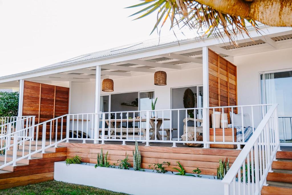 a home with a white deck and stairs at Skoon Seaside Accommodation in Skoenmakerskop