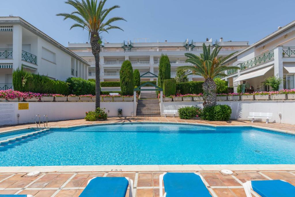 a swimming pool with blue lounge chairs in front of a building at Hauzify I Apartaments l'Estel in Sant Feliu de Guixols