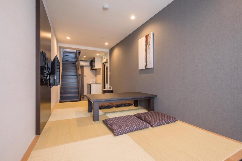 a living room with a table and a staircase at HOTEL R9 Kujukuri "ex Casual Resort COFF Ichinomiya" in Ichinomiya