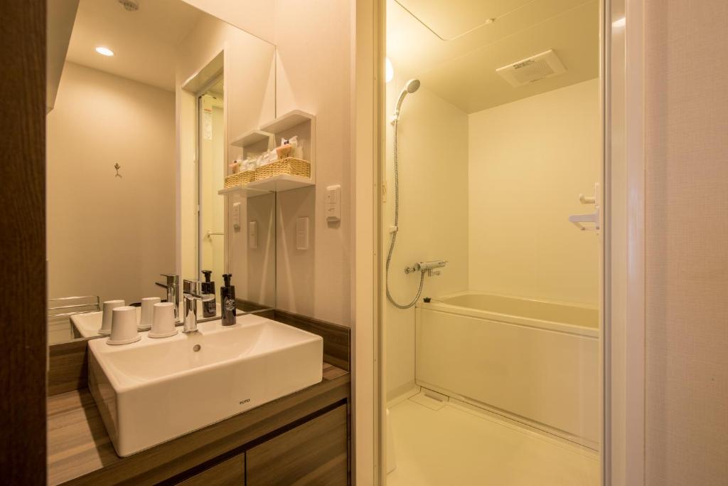 a white bathroom with a sink and a shower at HOTEL R9 Kujukuri "ex Casual Resort COFF Ichinomiya" in Ichinomiya