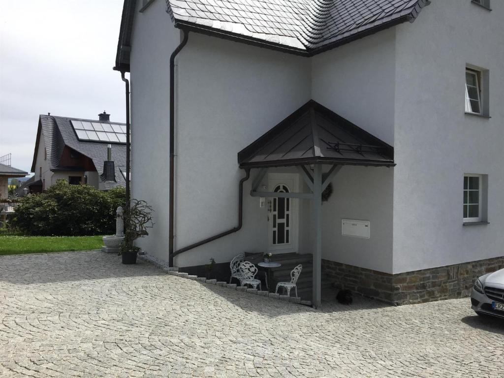 uma casa branca com uma mesa e uma cadeira em Ferienwohnung Erzgebirgsblick em Thermalbad Wiesenbad