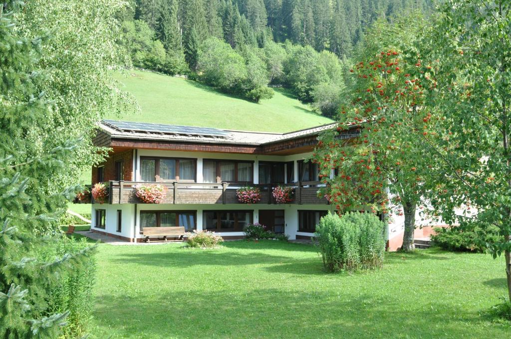 ein Haus auf einem Hügel mit einem grünen Hof in der Unterkunft Ferienwohnungen Bailom in Elbigenalp