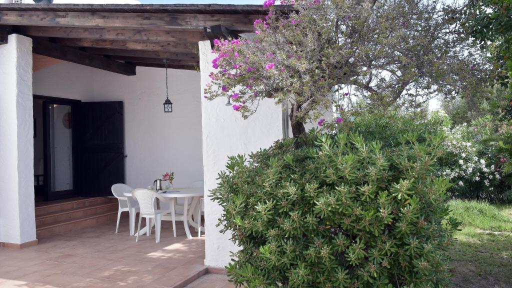 een patio met een tafel en stoelen en een boom bij Welcomely - Villa Adele in Costa Rei