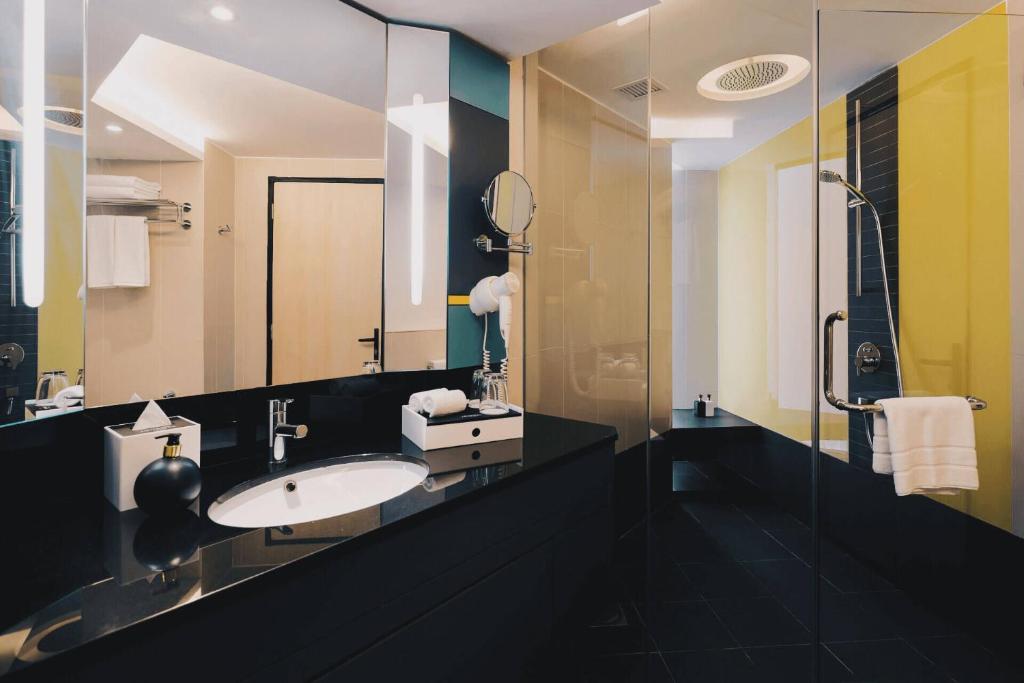 a bathroom with a sink and a glass shower at The Kuala Lumpur Journal Hotel in Kuala Lumpur