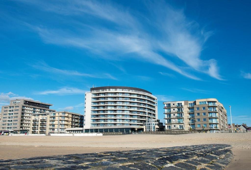 eine Gruppe von Gebäuden am Strand in der Nähe des Sandes in der Unterkunft Vayamundo Oostende - Apartments in Ostende