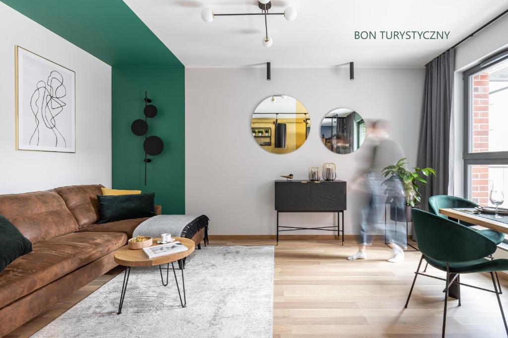 salon z brązową kanapą i zielonymi ścianami w obiekcie SMART LOQUM-apartament Browar Gdański-Wrzeszcz w Gdańsku