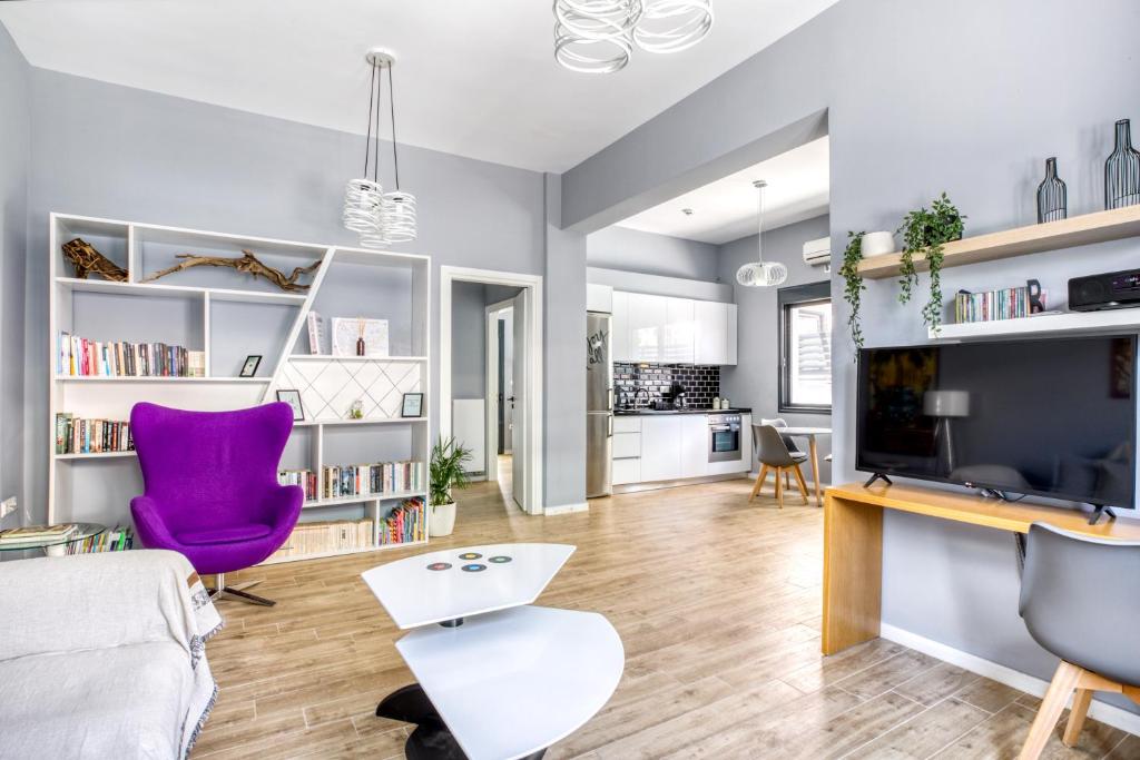 salon z fioletowym krzesłem i telewizorem w obiekcie Spacious flat with courtyard in Peristeri! w Atenach