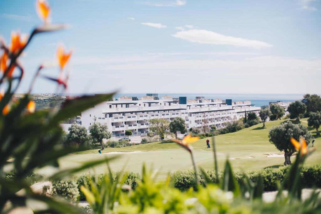 a hotel on a golf course with the ocean in the background at Ona Valle Romano Golf & Resort in Estepona
