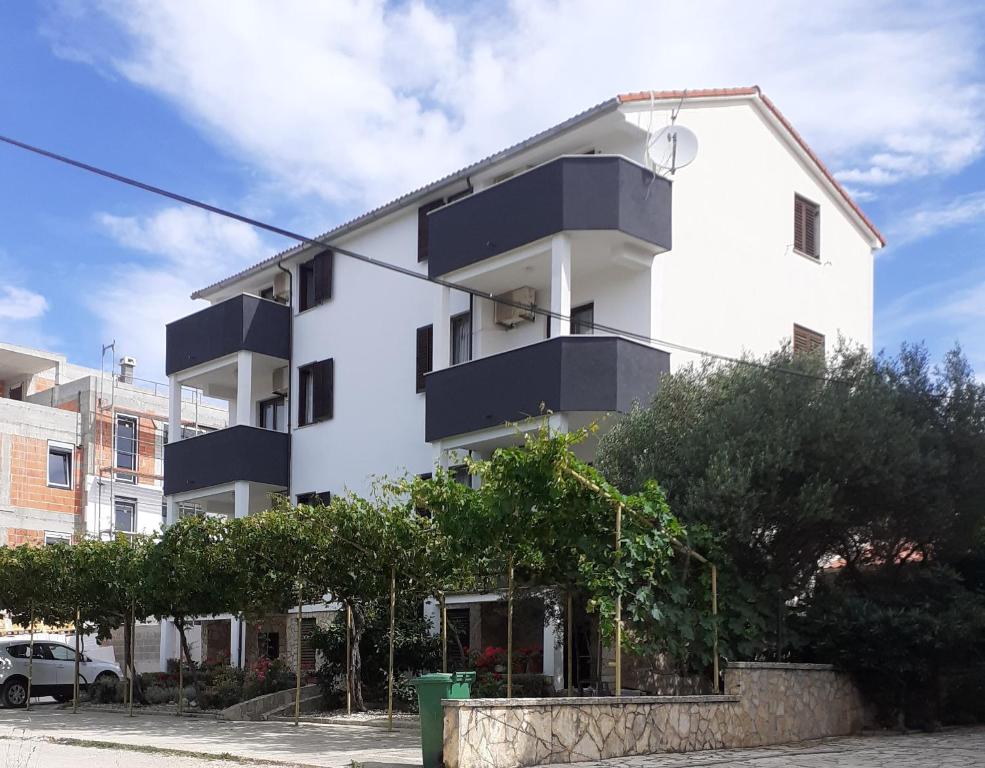 a white building with black balconies on it at Apartments Parać in Petrcane