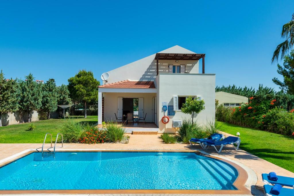 a villa with a swimming pool in front of a house at Athena Villa in Kolimbia