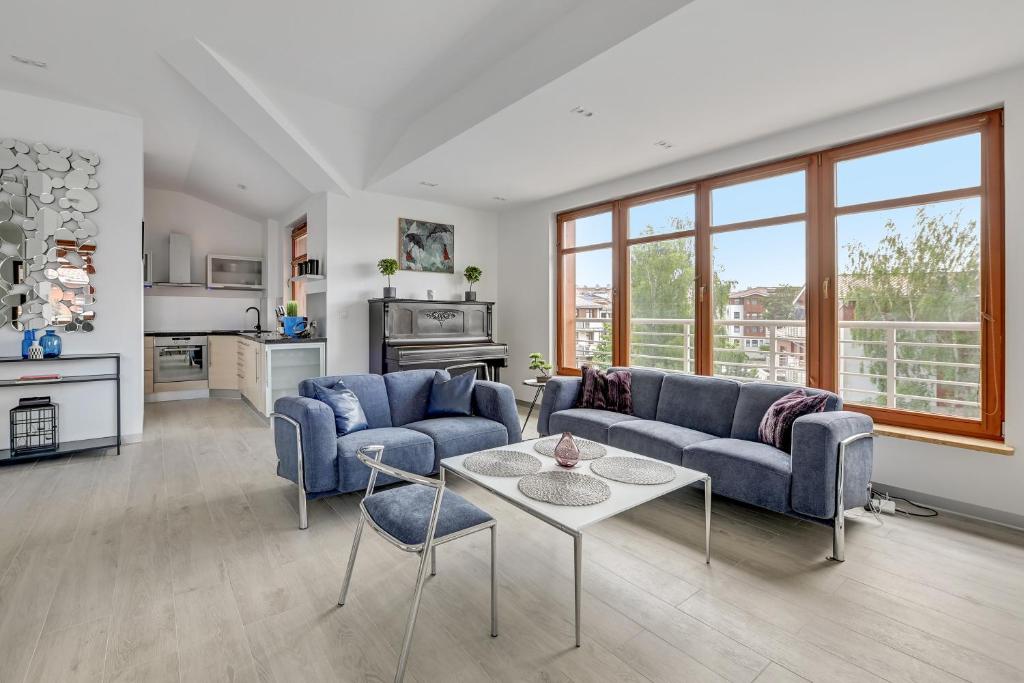 a living room with two blue couches and a table at Grand Apartments - Neptun Park. in Gdańsk