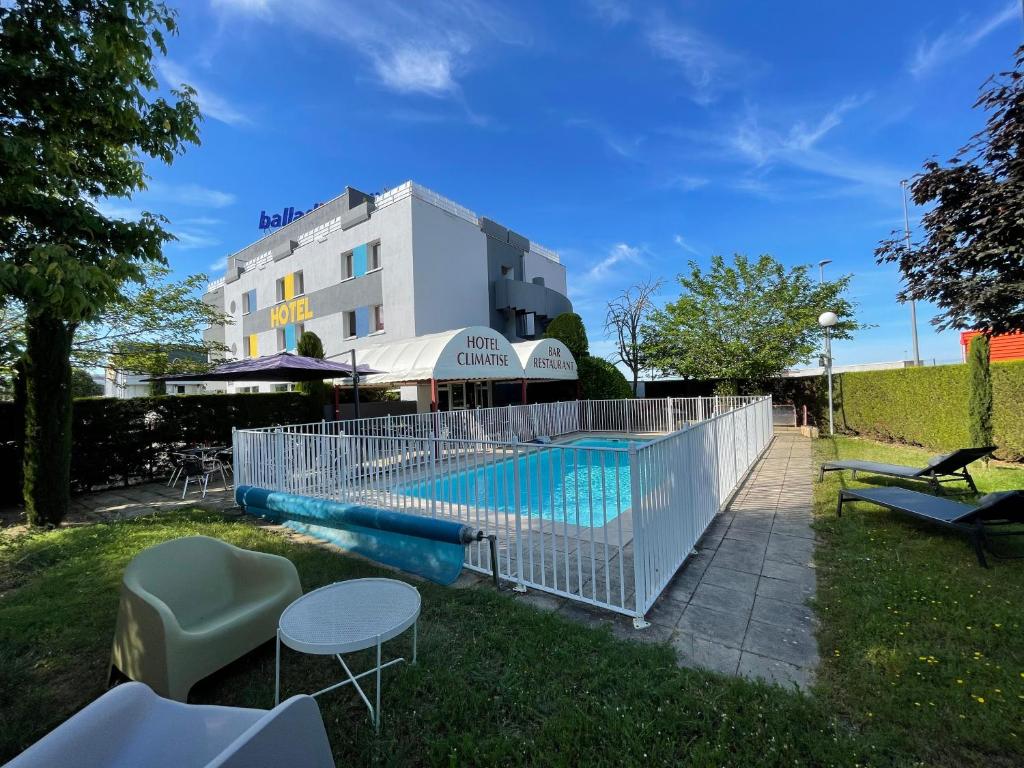 een zwembad met tafels en stoelen naast een gebouw bij Hôtel Restaurant Kyriad Direct DIJON NORD - Zenith - Toison d'Or in Dijon