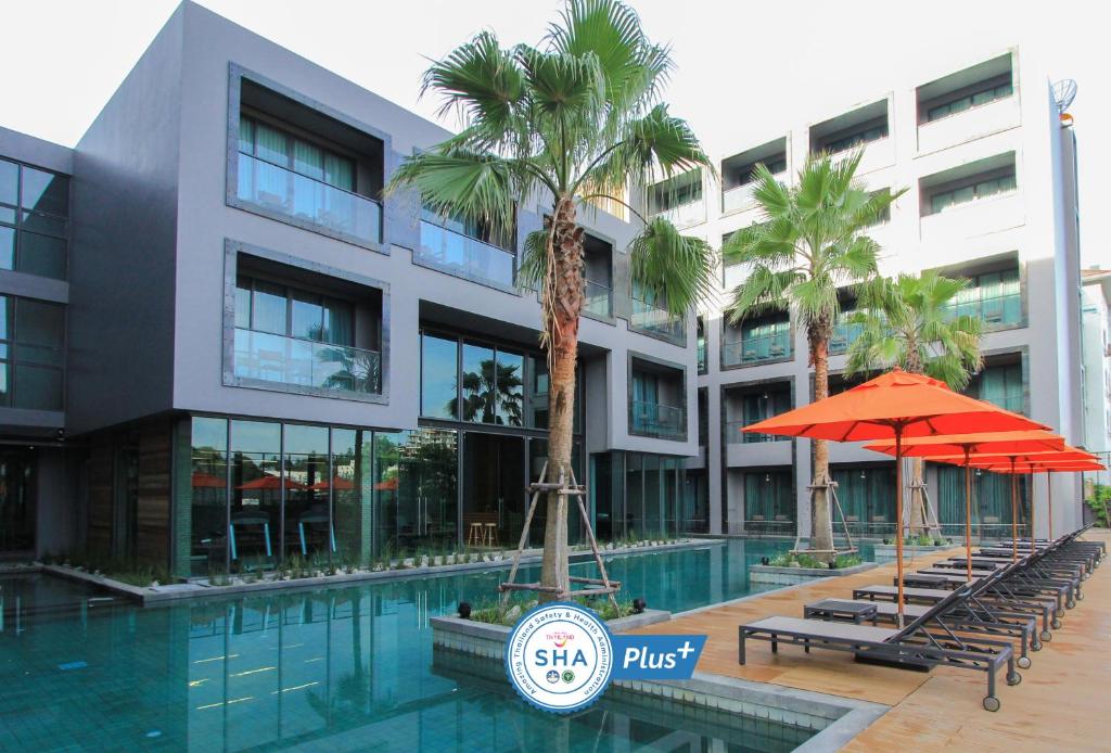 un hotel con piscina y palmeras frente a un edificio en Sugar Marina Hotel-SURF-Kata Beach - SHA Plus, en Kata Beach