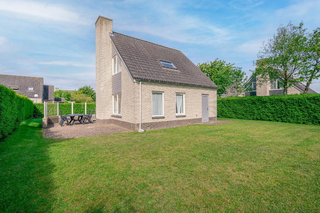 una casa con un banco delante de un patio en Villapark Kamperfoelie 77, en De Koog