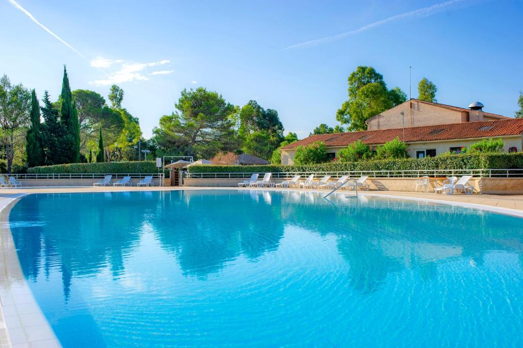 a large swimming pool with blue water and white chairs at VTF Le Castelet in Saint-Aygulf