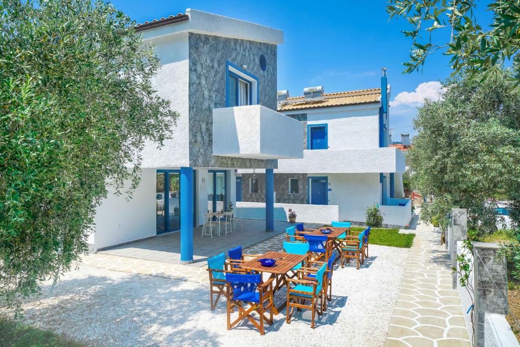 een patio met blauwe tafels en stoelen voor een huis bij Mikres Kyklades in Skala Potamias